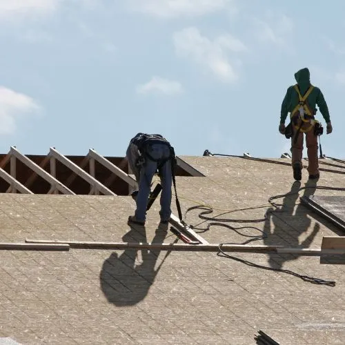 Roofers installing roof underlayment on a new roof deck